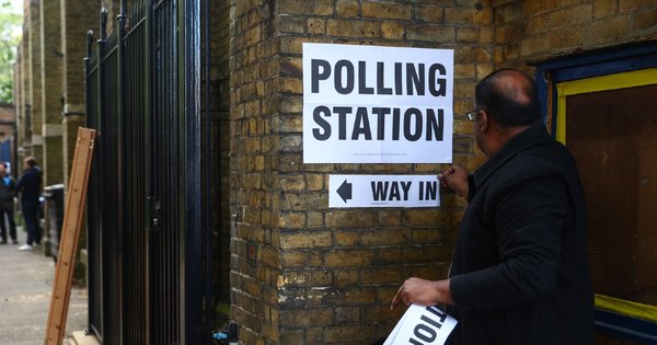 A person putting up a sign outside a polling station in London.