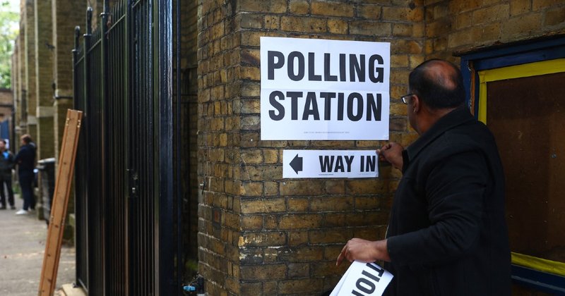 A person putting up a sign outside a polling station in London.