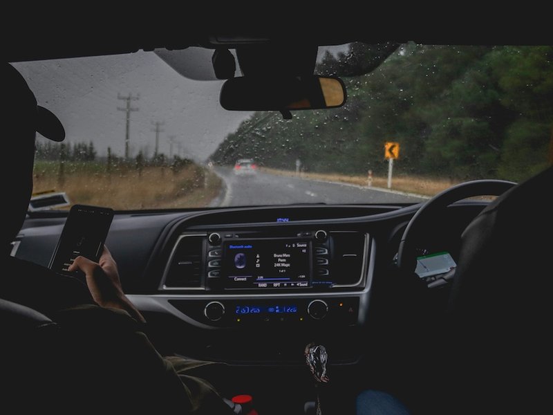 A picture of two people in the front of a car with the radio on.