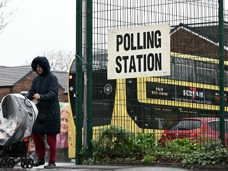 A woman with a pushchair outside a polling station in Gorton and Denton
