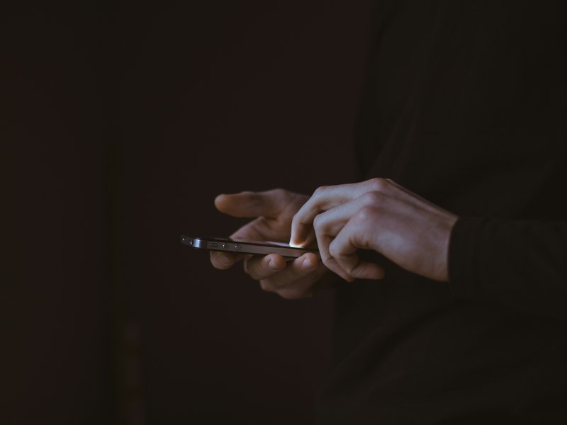 A dark photo showing someone using a phone.