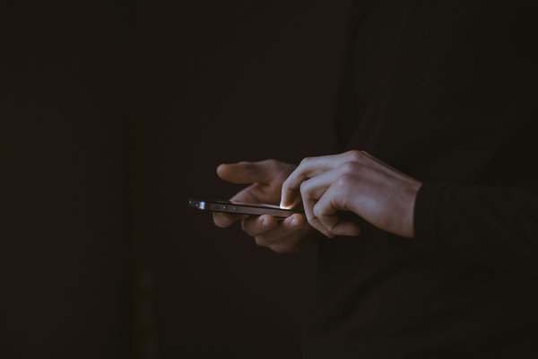 A dark photo showing someone using a phone.