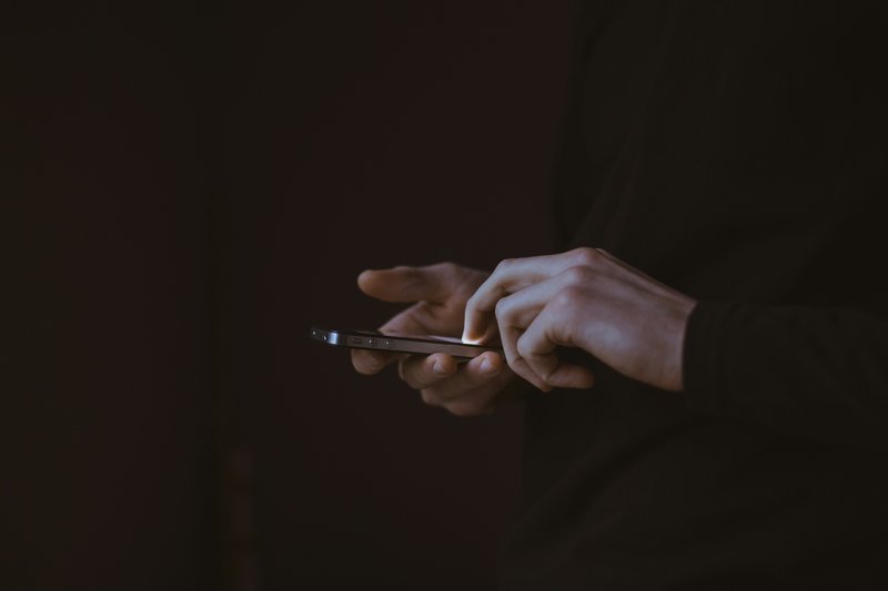 A dark photo showing someone using a phone.