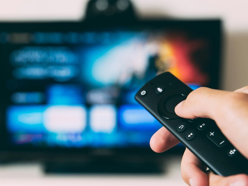 A photo of someone using a television and a remote.