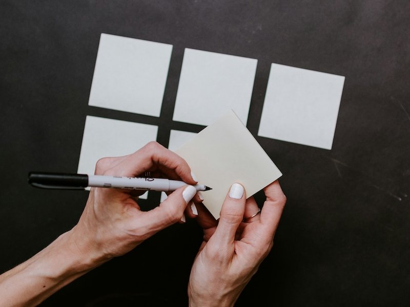 A hand about to write on blank sticky notes