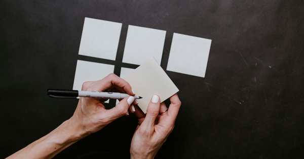 A hand about to write on blank sticky notes