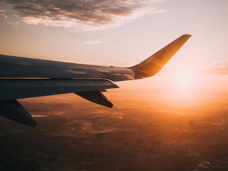 Wing of a plane flying at sunset