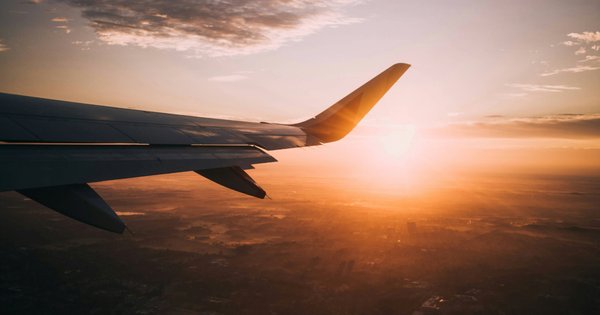 Wing of a plane flying at sunset