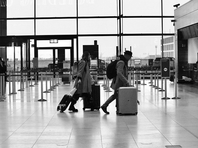 A man and a woman carrying luggage through an airport terminal.