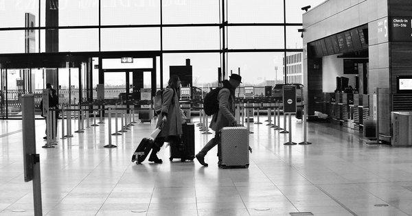 A man and a woman carrying luggage through an airport terminal.