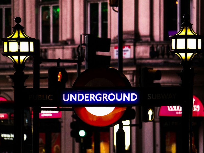 A photo of a London Underground sign at night.