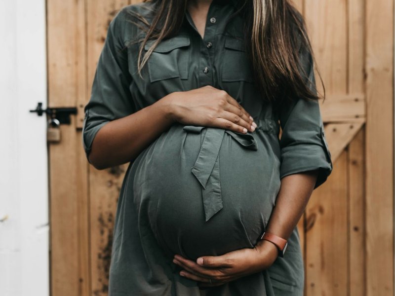 A pregnant woman with her hands around the bump