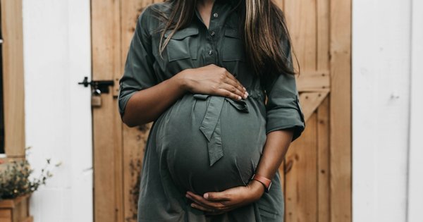 A pregnant woman with her hands around the bump