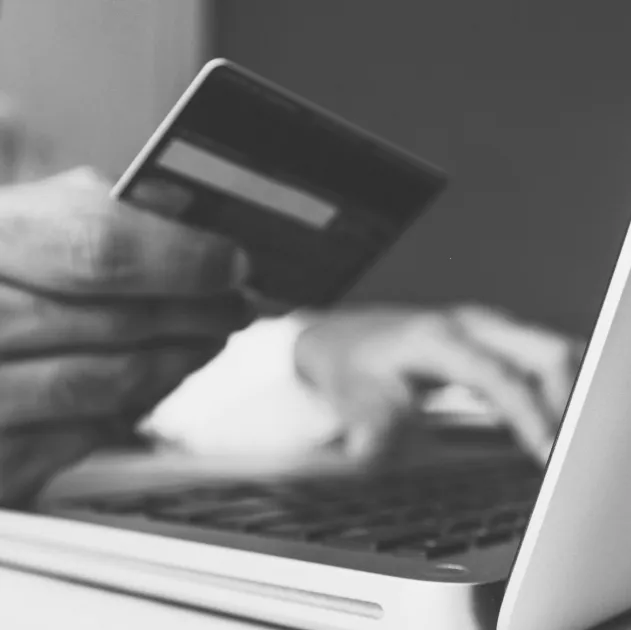 Person holding a bank card while using their laptop.