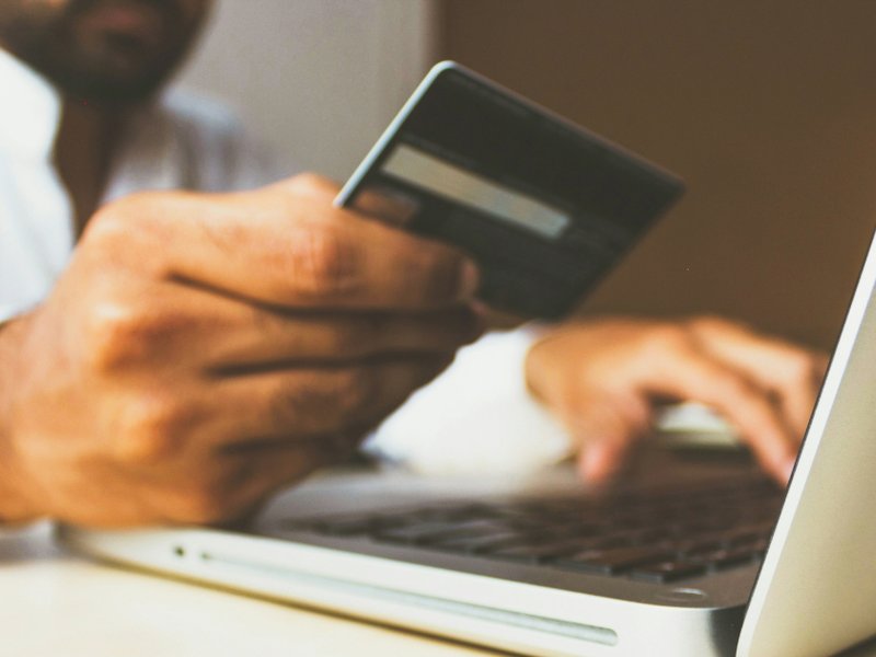 Person holding a bank card while using their laptop.