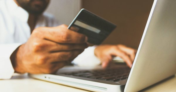 Person holding a bank card while using their laptop.