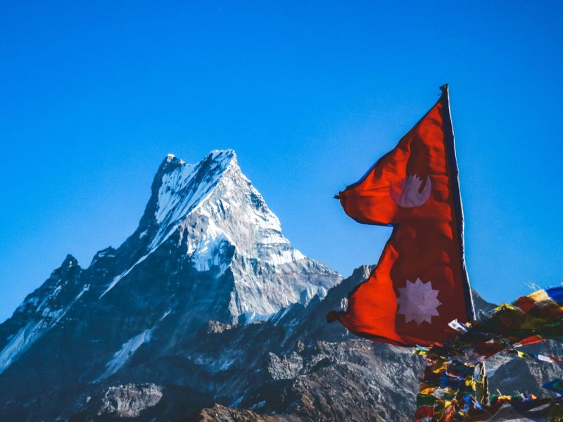 An image of the flag of Nepal in front of a snow covered mountain