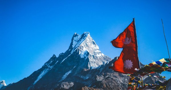 An image of the flag of Nepal in front of a snow covered mountain
