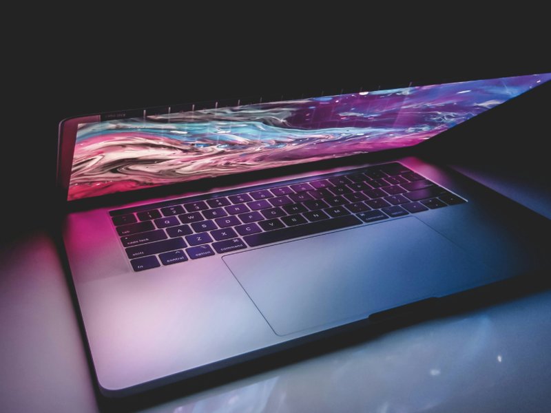 An image of a desk and a laptop in a dark room.