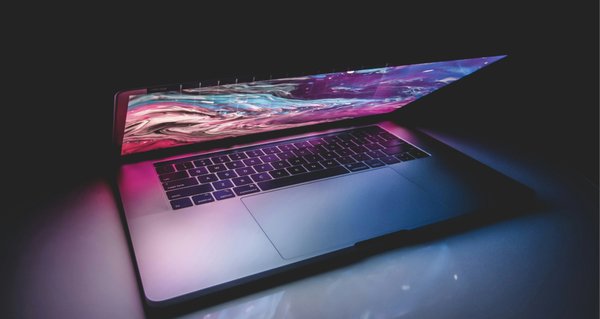 An image of a desk and a laptop in a dark room.