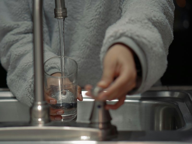 Person filling a glass of water from the tap