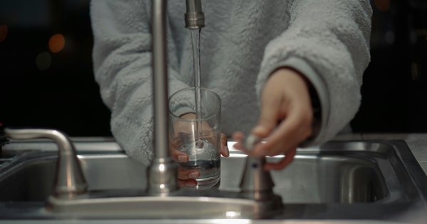 Person filling a glass of water from the tap