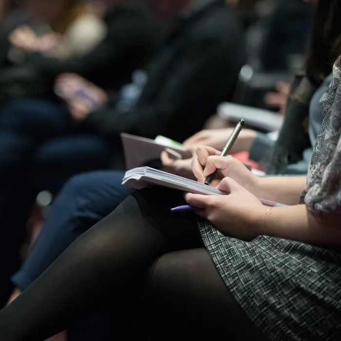A person writing down notes at a conference