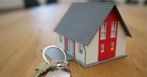 An image of a miniature house with a set of keys beside it.