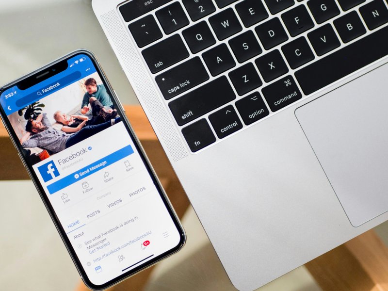 Image of a phone with Facebook open beside a laptop.