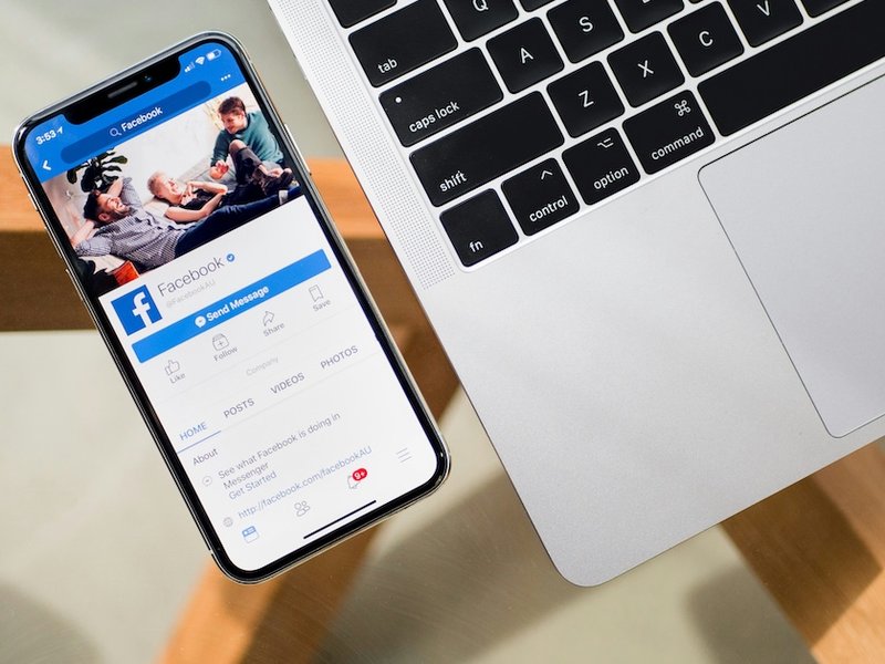 A phone displaying Facebook alongside a laptop