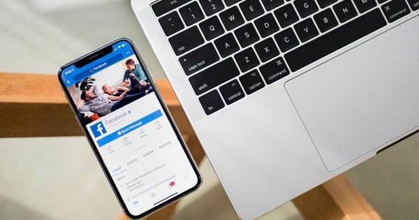 Image of a phone with Facebook open beside a laptop.