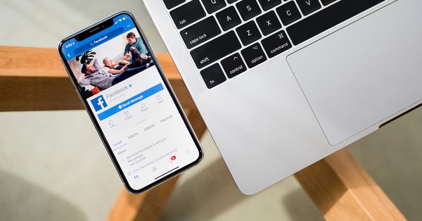 A phone displaying Facebook alongside a laptop
