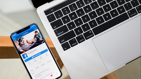 Facebook open on a phone besides a laptop.